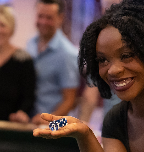 Luck at table games is the dream of every gambler and superstitions, like blowing on dice, can be seen in almost every game. This gambler is having fun while trying out her luck.